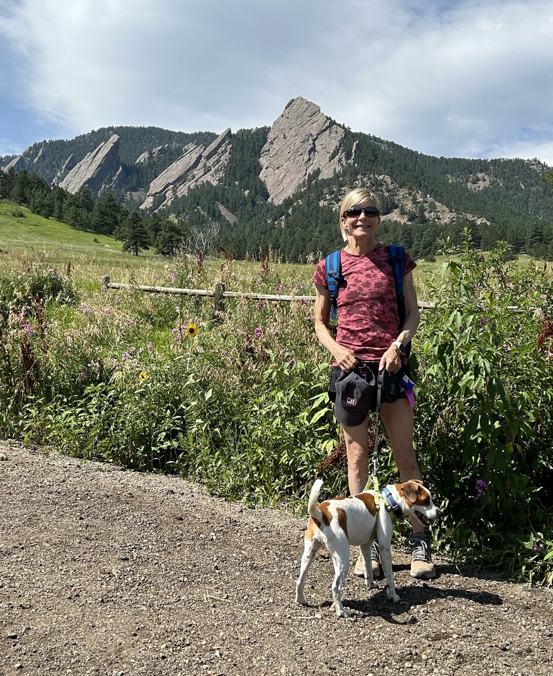 Nina Caron hiking a mountain trail with her dog beneath the Flatirons