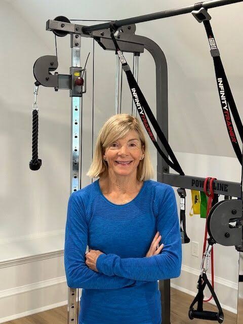 Nina Caron standing with arms crossed in her training studio, cable machine behind her