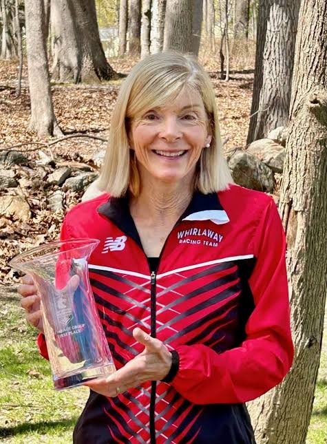 Nina Caron in her Whirlaway Racing Team jacket holding a first-place age-group trophy