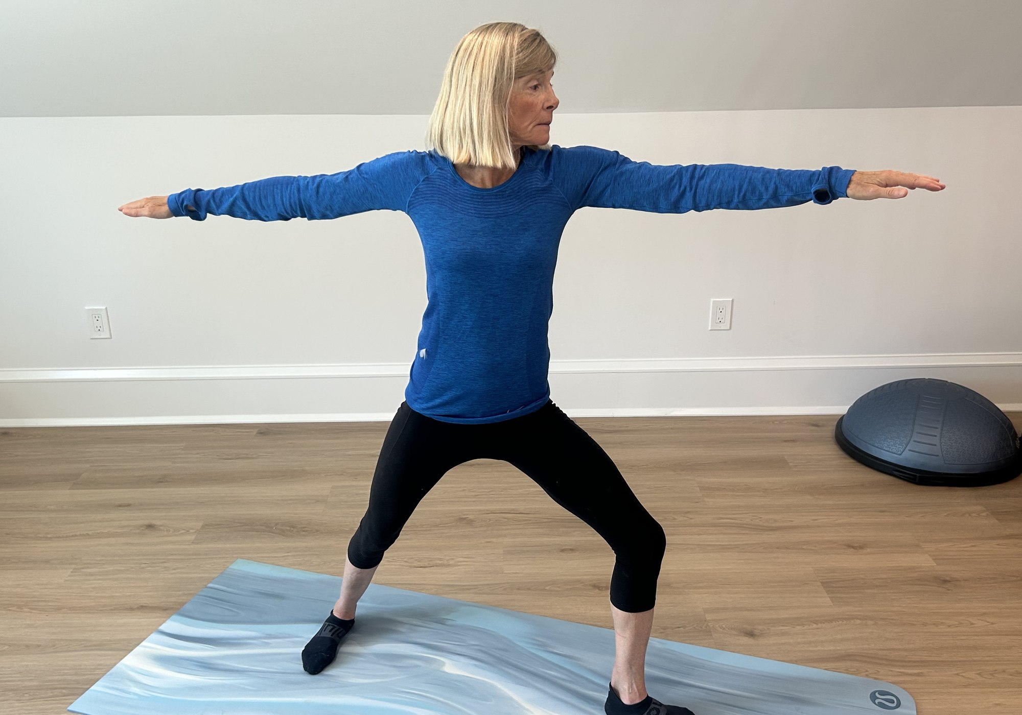 Nina Caron holding warrior II pose in her home studio