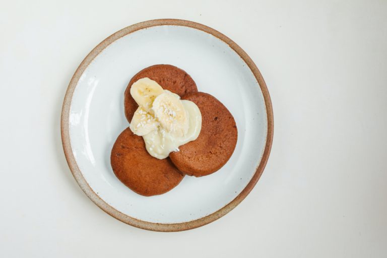 Banana oat cookies on a plate topped with banana slices