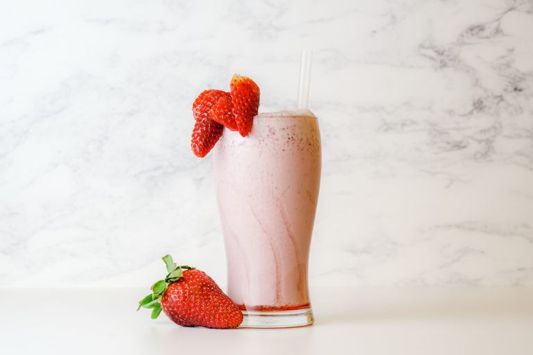 A strawberry protein smoothie in a tall glass