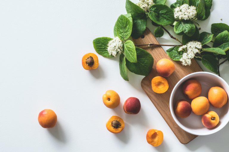 Fresh apricots and produce on a wooden cutting board