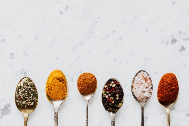 Spoons of chili spices — turmeric, chili powder, peppercorns, and salt
