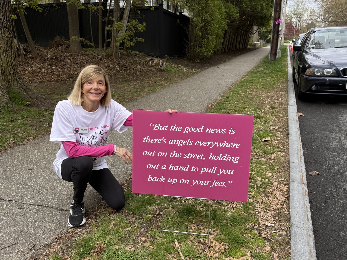 Nina Caron kneeling beside an inspirational sign along the Step Up for Colleen 5K course